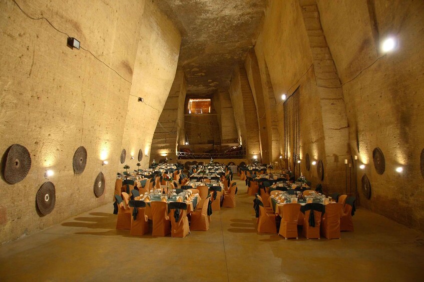 An underground dining hall with circular wall decorations and tables set for a meal. 4