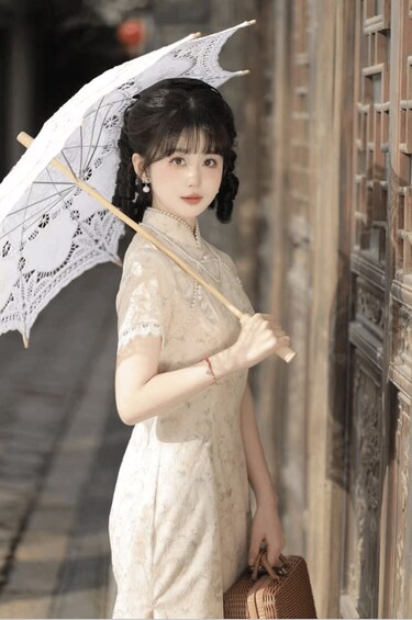 A person in a traditional dress holding an umbrella and a small bag. 3