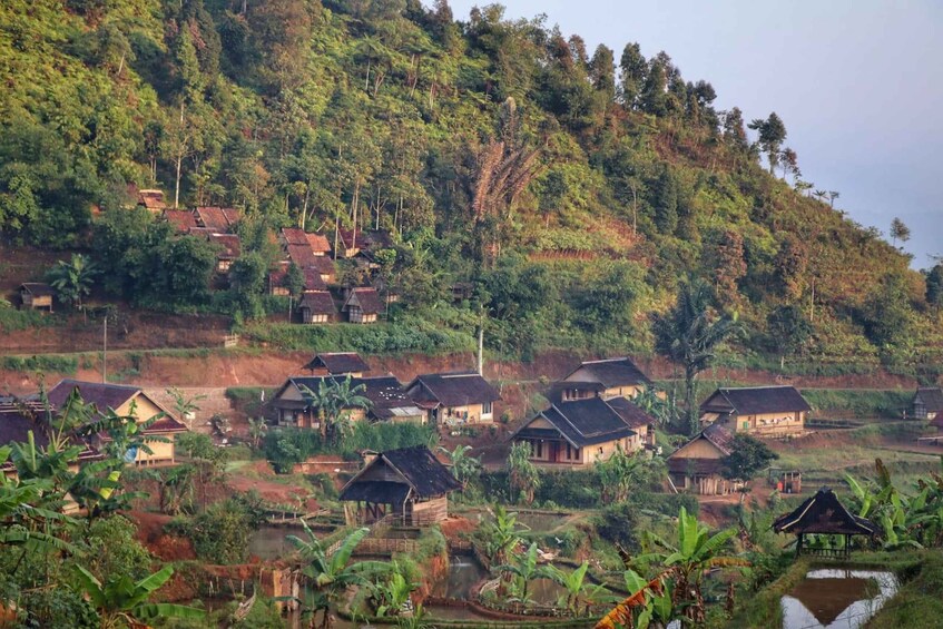 A village with traditional houses nestled in a hilly landscape with dense vegetation. 1
