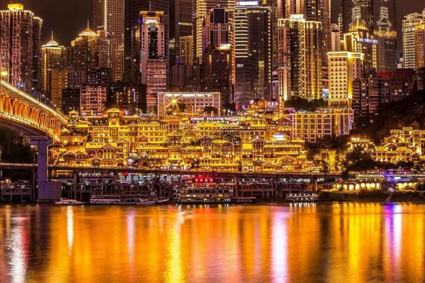 A cityscape at night with illuminated buildings and a bridge reflecting on the water. 5