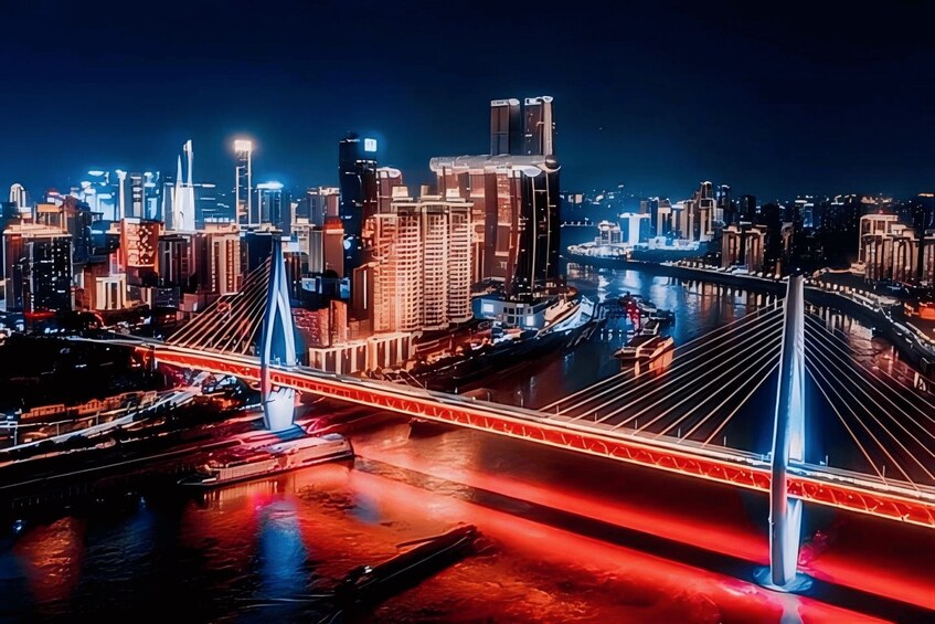 A nighttime cityscape with illuminated buildings, a prominent bridge with red lights, and a river reflecting the city lights. 1