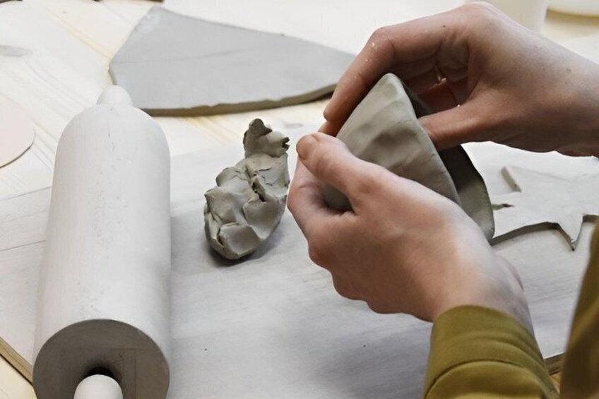 Hands shaping clay on a workbench. 2