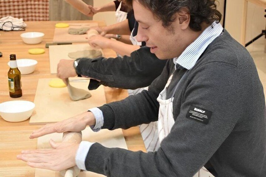 People engaged in a cooking activity, with bowls and a bottle on the table. 1