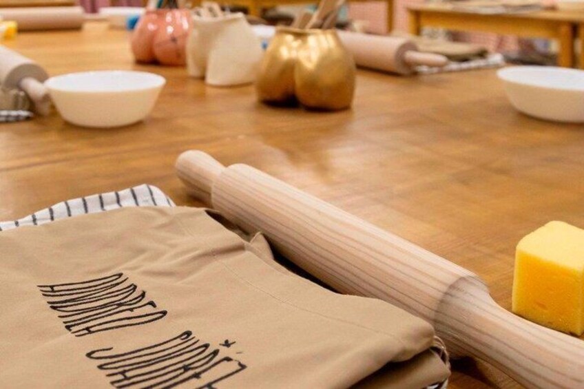 A kitchen with a rolling pin, a cloth, and a yellow sponge on a wooden table. 5
