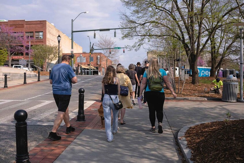 Pedestrians crossing a street with bollards, a crosswalk, and a building with a sign. 4