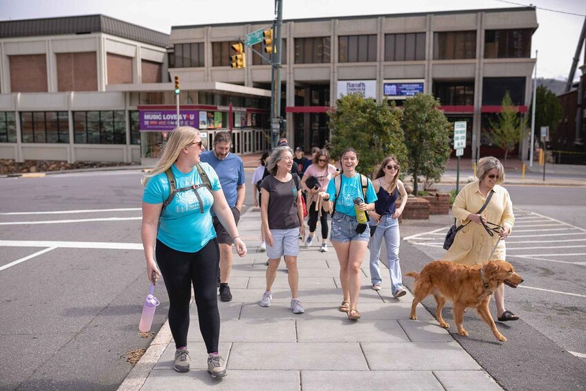 A group of people crossing a street with a dog. 1