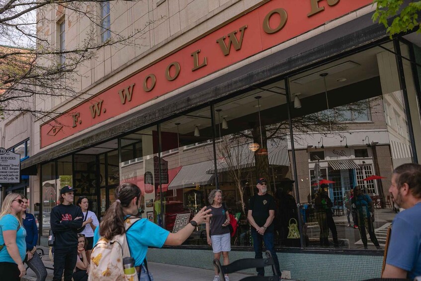 A storefront with a sign reading 'F.W. WOOLWORTHS' and people standing outside. 3