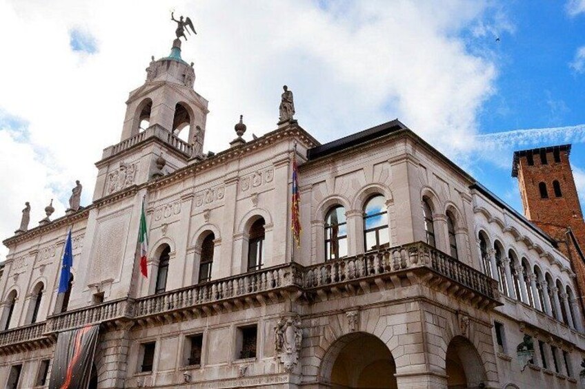 A historic building with a bell tower, arched windows, and flags. 1