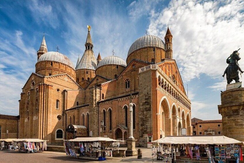 A historic church with multiple domes and a statue in front. 4