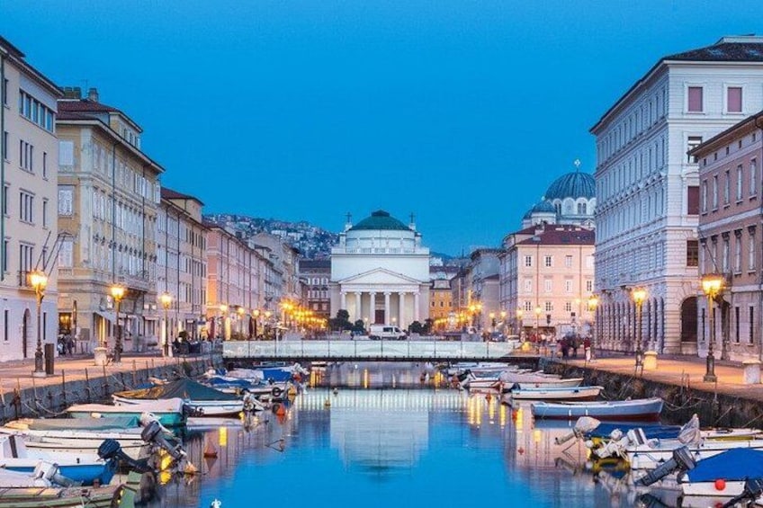 A waterfront with boats docked, a domed building, and illuminated street lamps. 5