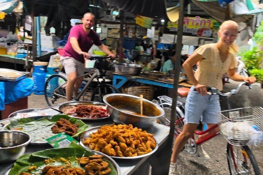 A street food vendor stall with various dishes and a bicycle. 4