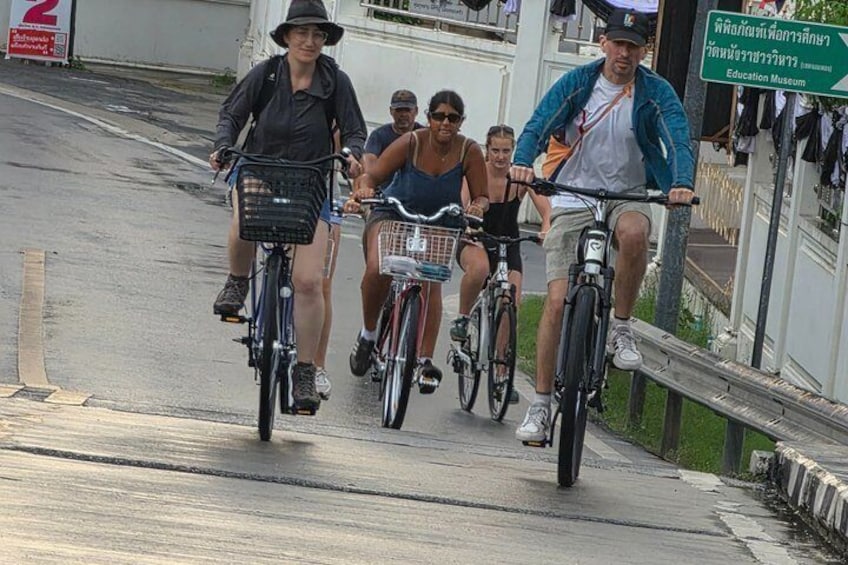 A group of people riding bicycles on a paved path. 1