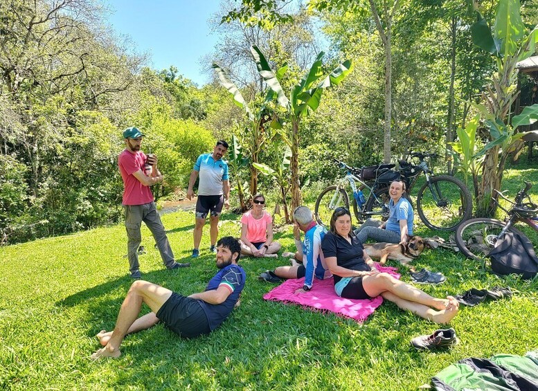 A group of people exercising outdoors on a grassy field with trees and bicycles in the background. 3