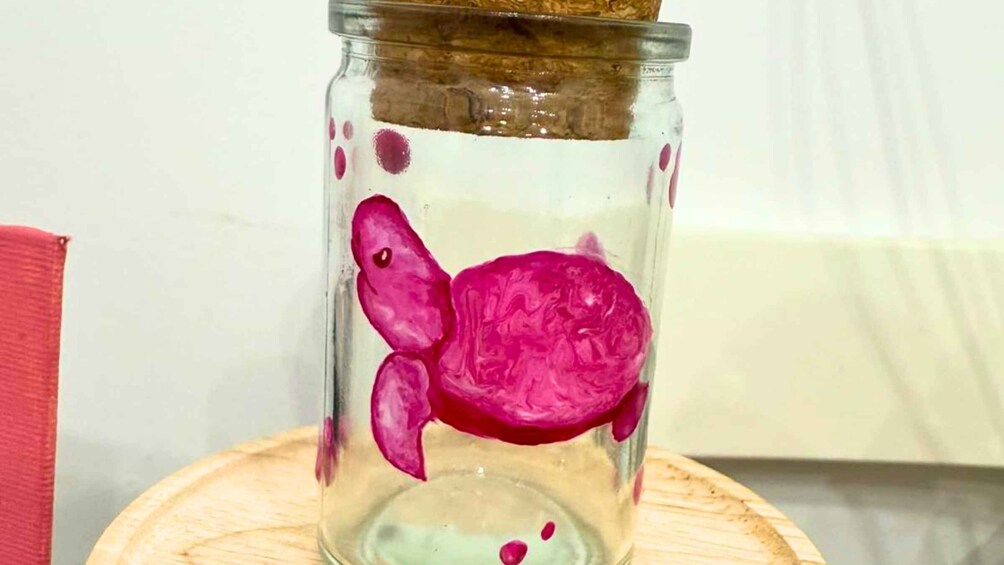 A glass jar with a pink turtle inside, placed on a wooden surface. 5