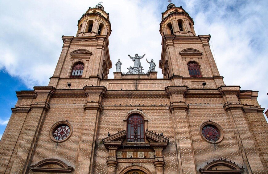 A large brick church with two towers, a central statue, and circular windows. 3