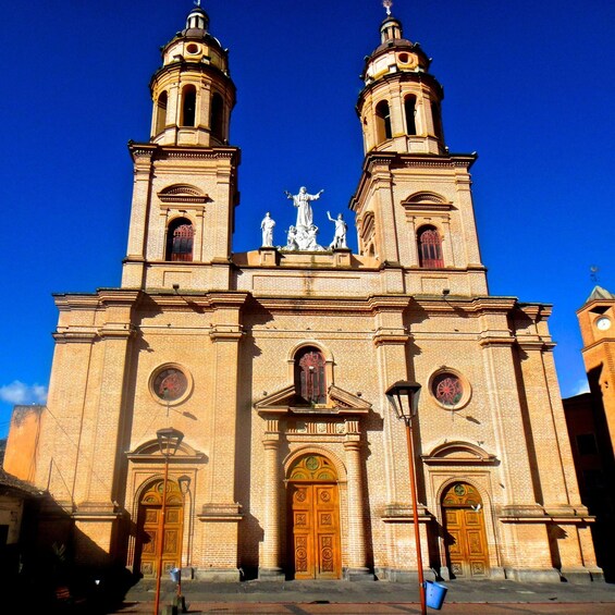 A large brick church with two towers, ornate doors, and statues on the facade. 2