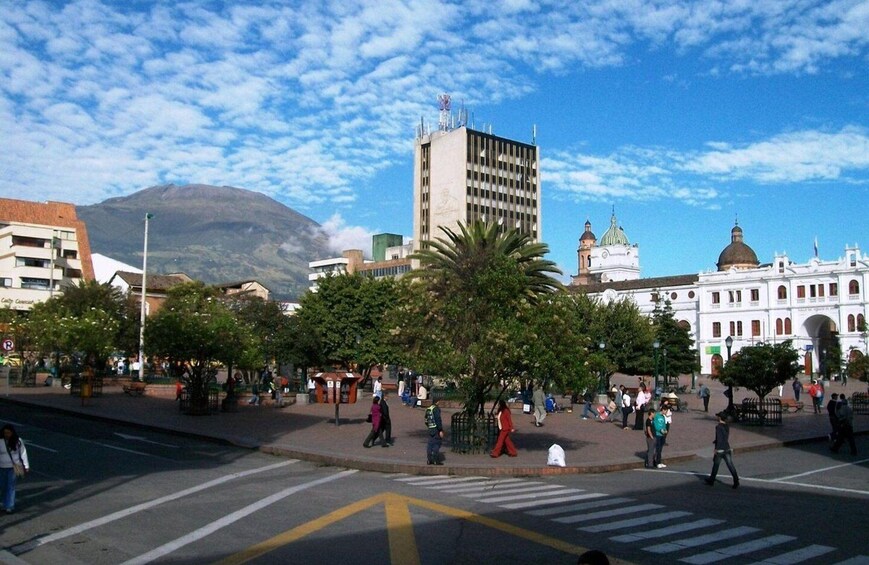 A busy urban square with pedestrians, a crosswalk, and historic buildings. 1