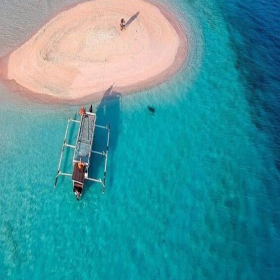 An aerial view of a small island with clear turquoise waters and a dock extending from the shore. 3