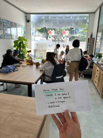 A person holding a paper with tour details in a modern office setting. 5