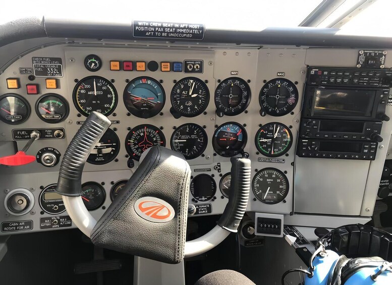 A cockpit with multiple gauges, a steering wheel, and a warning label. 3