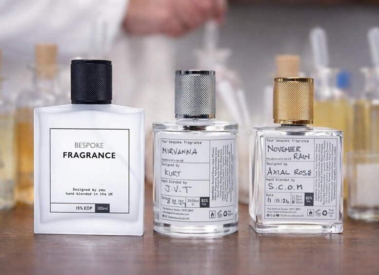 Three perfume bottles with labels, one white and two transparent, on a table. 3
