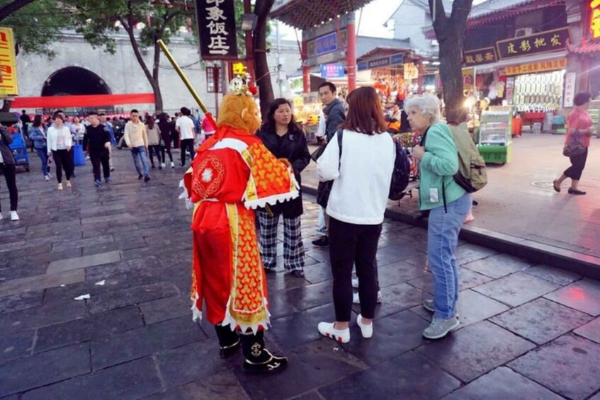 A street scene with people, a person in a red costume, and traditional architecture. 2