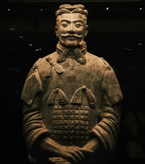 A terracotta statue with a detailed uniform, including a bow and a chest plate with heart-shaped patterns. 5