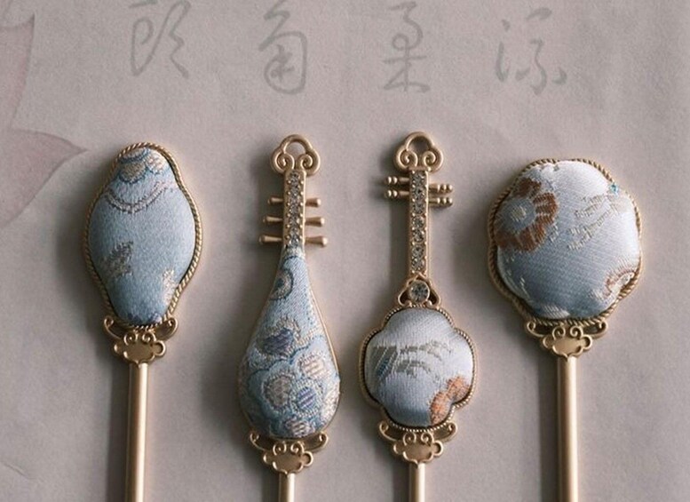 Four decorative keychains with blue fabric and gold accents. 4