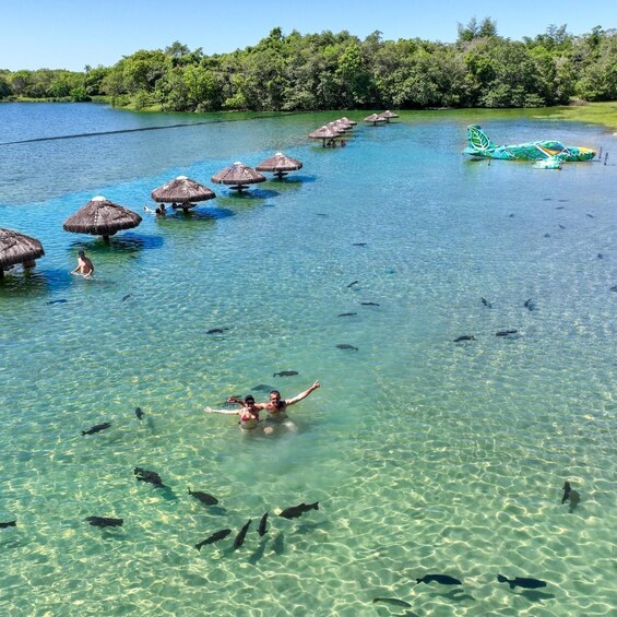 A clear tropical water body with people swimming and a small boat. 5