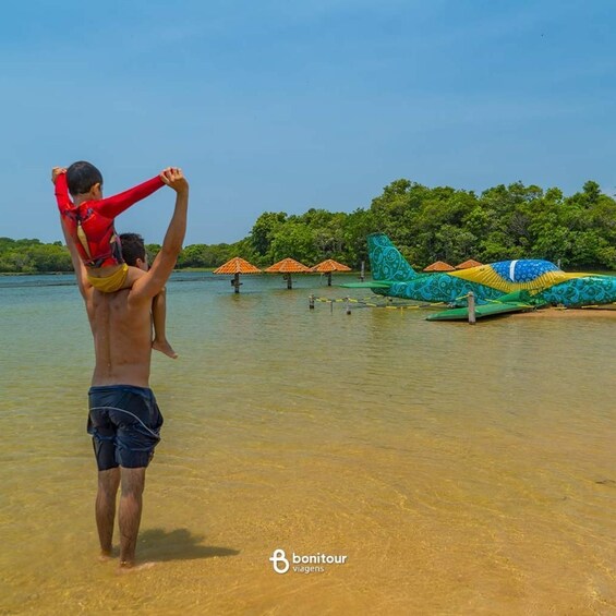 A man carrying a child on his shoulders by a water body with floating structures and umbrellas. 3