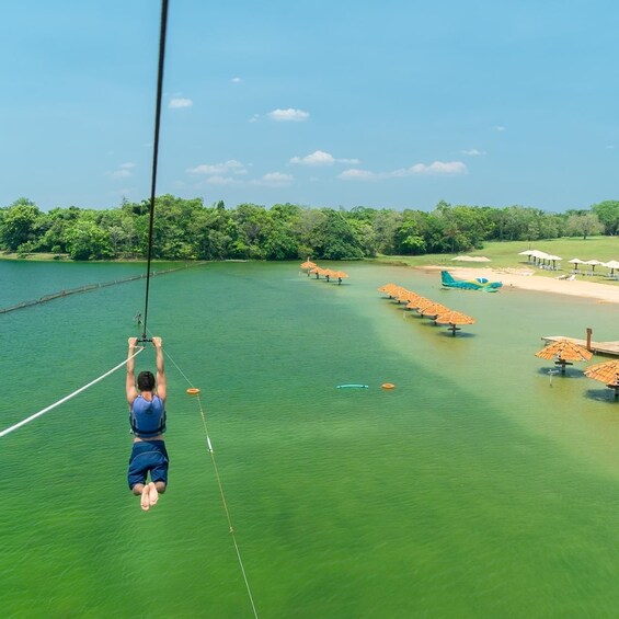 A person bungee jumping from a bridge over a lake with trees and beach umbrellas in the background. 2
