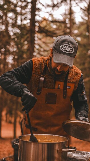 A person cooking outdoors with a pot on a portable stove. 4