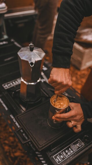 A person using a coffee grinder to prepare a drink. 5