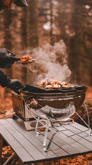 A person grilling mushrooms on an open fire in a forest. 2