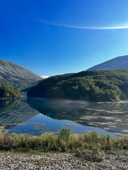 A calm lake surrounded by hills and dense forest. 3