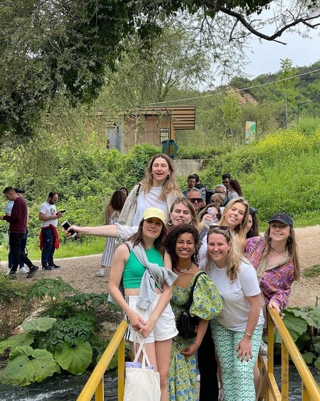 A group of people on a bridge with greenery and a building in the background. 2
