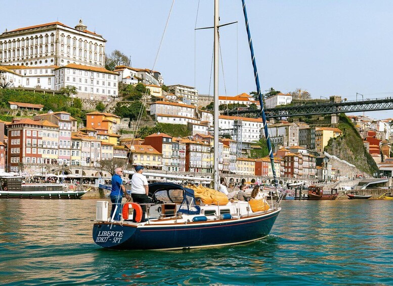 A boat named 'LIBERTÉ' on calm waters with a cityscape in the background, including historic buildings and a bridge. 3