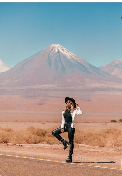 A person standing on a road with a mountain in the background. 3