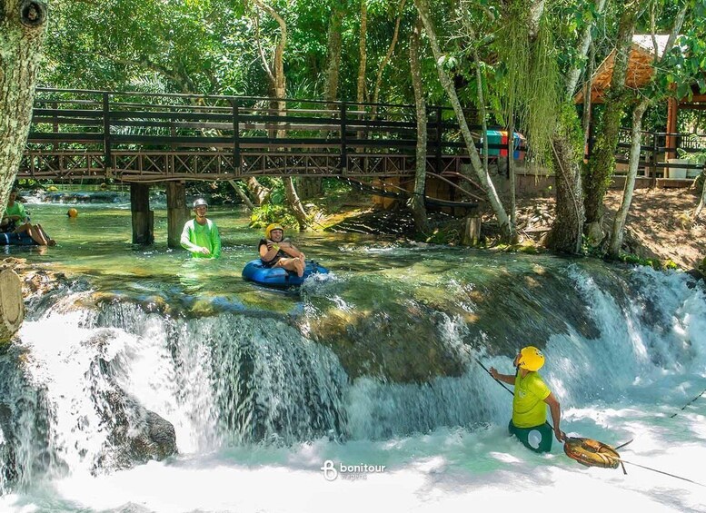 A waterfall, people on inflatable tubes, and a bridge. 2