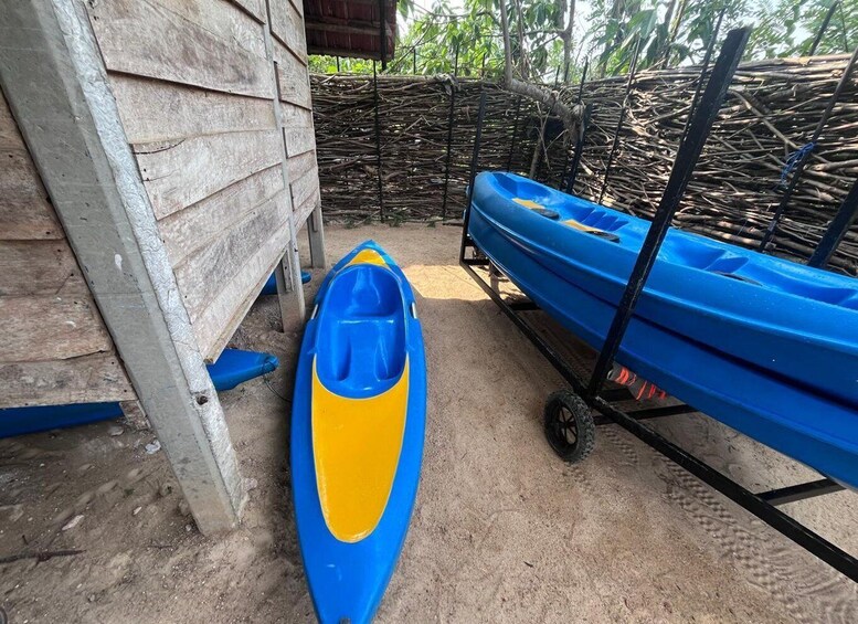 A blue and yellow kayak, a wooden structure, and a cart with kayaks. 2