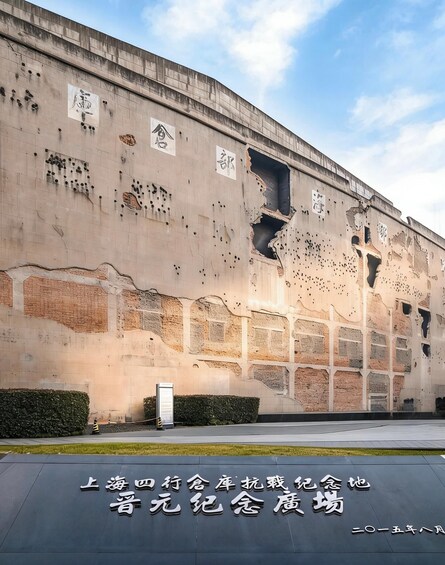 A large building with bullet holes and damage, surrounded by a well-maintained lawn and a sign with Chinese characters. 5