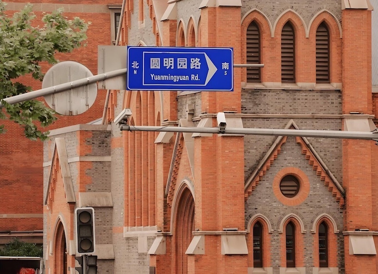 A blue street sign for Yuanmingyuan Rd. with a brick building in the background. 1
