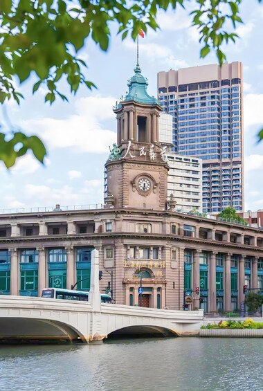 A historic building with a clock tower, a bridge, and a modern high-rise building in the background. 4