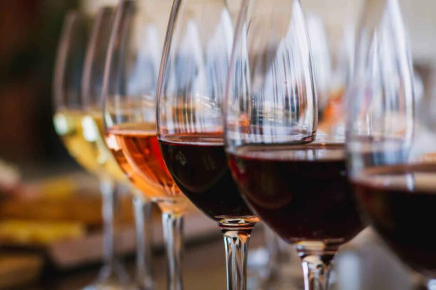 A row of wine glasses filled with different colored liquids. 3