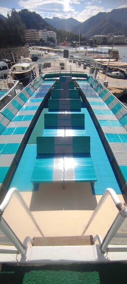 A boat deck with blue and white checkered flooring, metal railings, and a row of green cushioned seats. 4