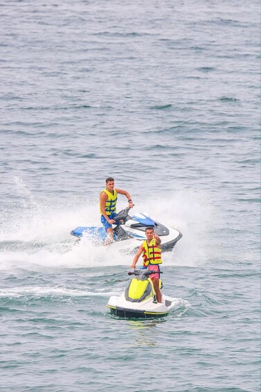 Two people jet skiing on a body of water. 1