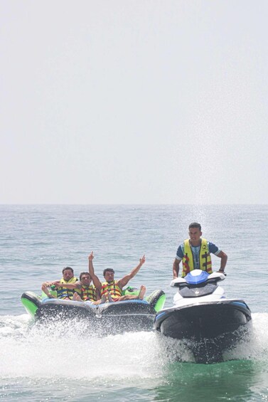 A jet ski with passengers wearing life jackets, moving through water. 5