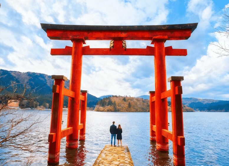 A red torii gate with a stone pathway leading to it over water, surrounded by mountains. 5