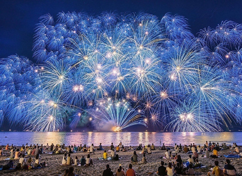 A beach with people watching fireworks. 1