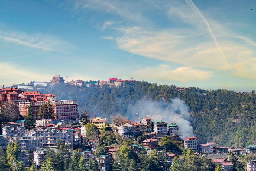 A mountainous town with buildings, smoke rising from a chimney, and a clear sky. 1